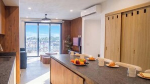 Eine moderne Küche mit einer zentralen Kochinsel, Holzschränken und einer großen Schiebetür, die auf einen Balkon führt.