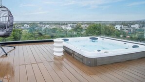 Eine Dachterrasse mit Whirlpool, Hängesessel und Blick auf die Stadtlandschaft.