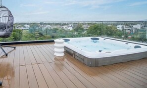 Eine Dachterrasse mit Whirlpool, Hängesessel und Blick auf die Stadtlandschaft.