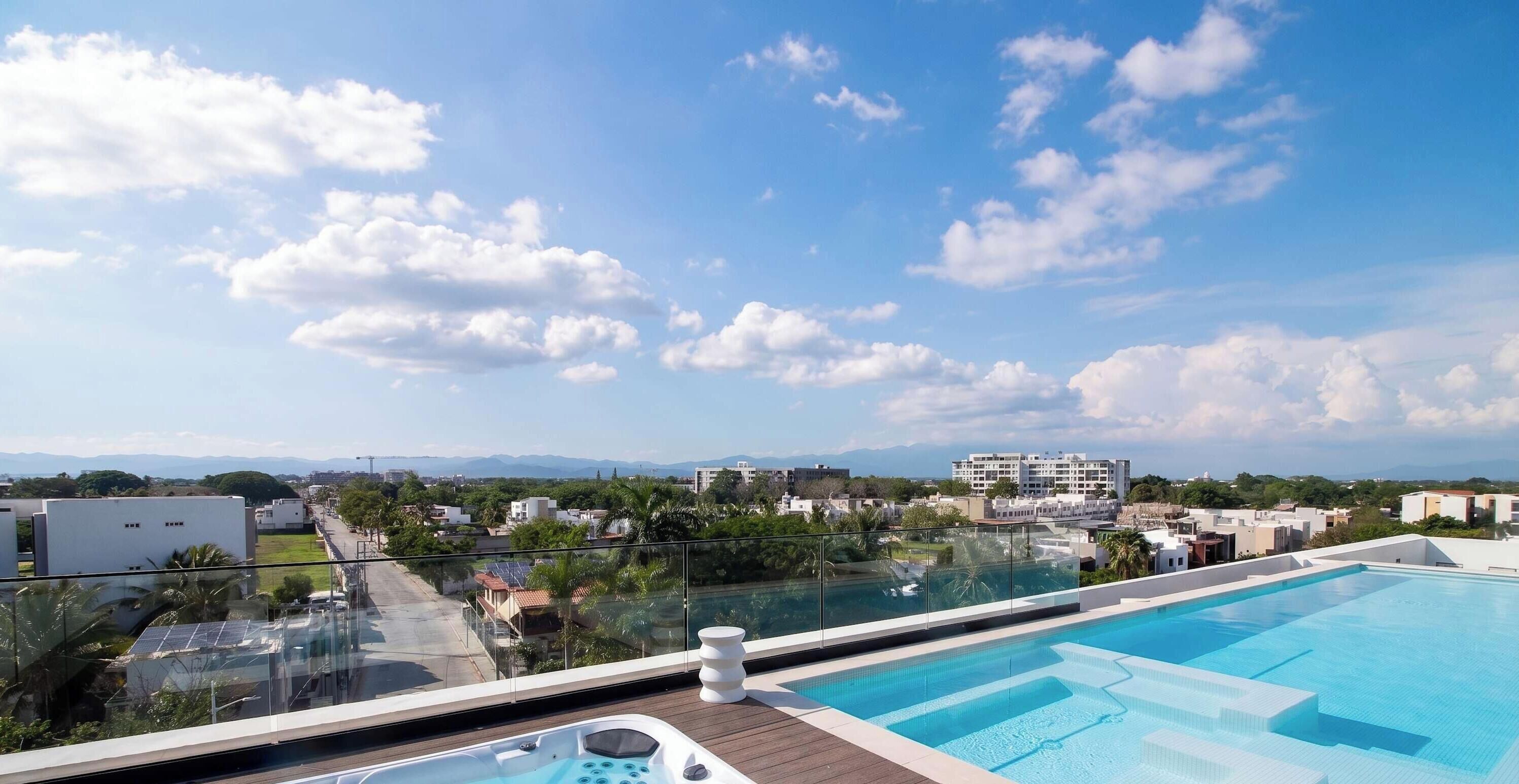 A rooftop swimming pool with a clear view of the surrounding cityscape and mountains.