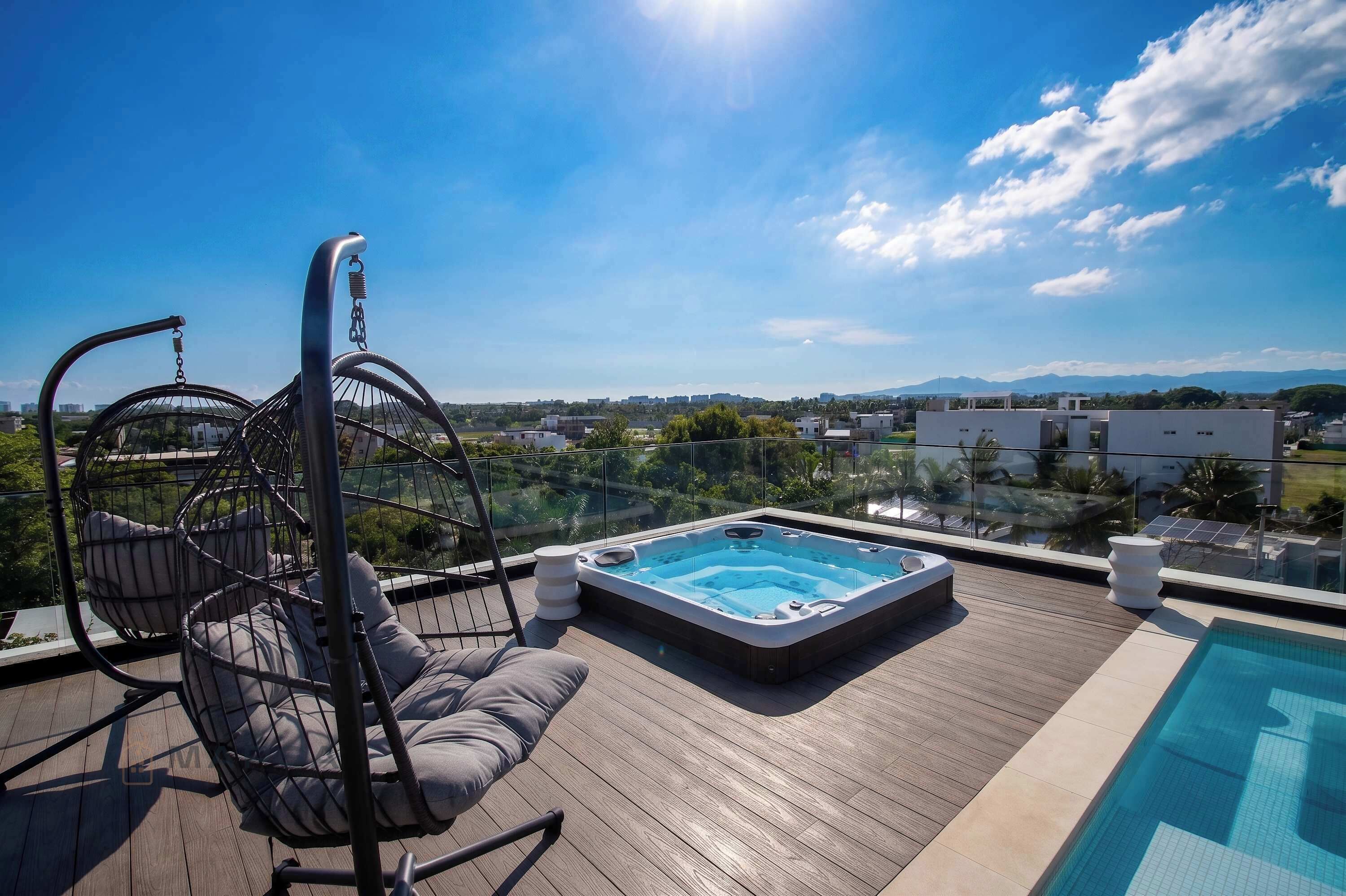 Une terrasse sur le toit avec un jacuzzi, un fauteuil suspendu et une vue sur le paysage urbain.