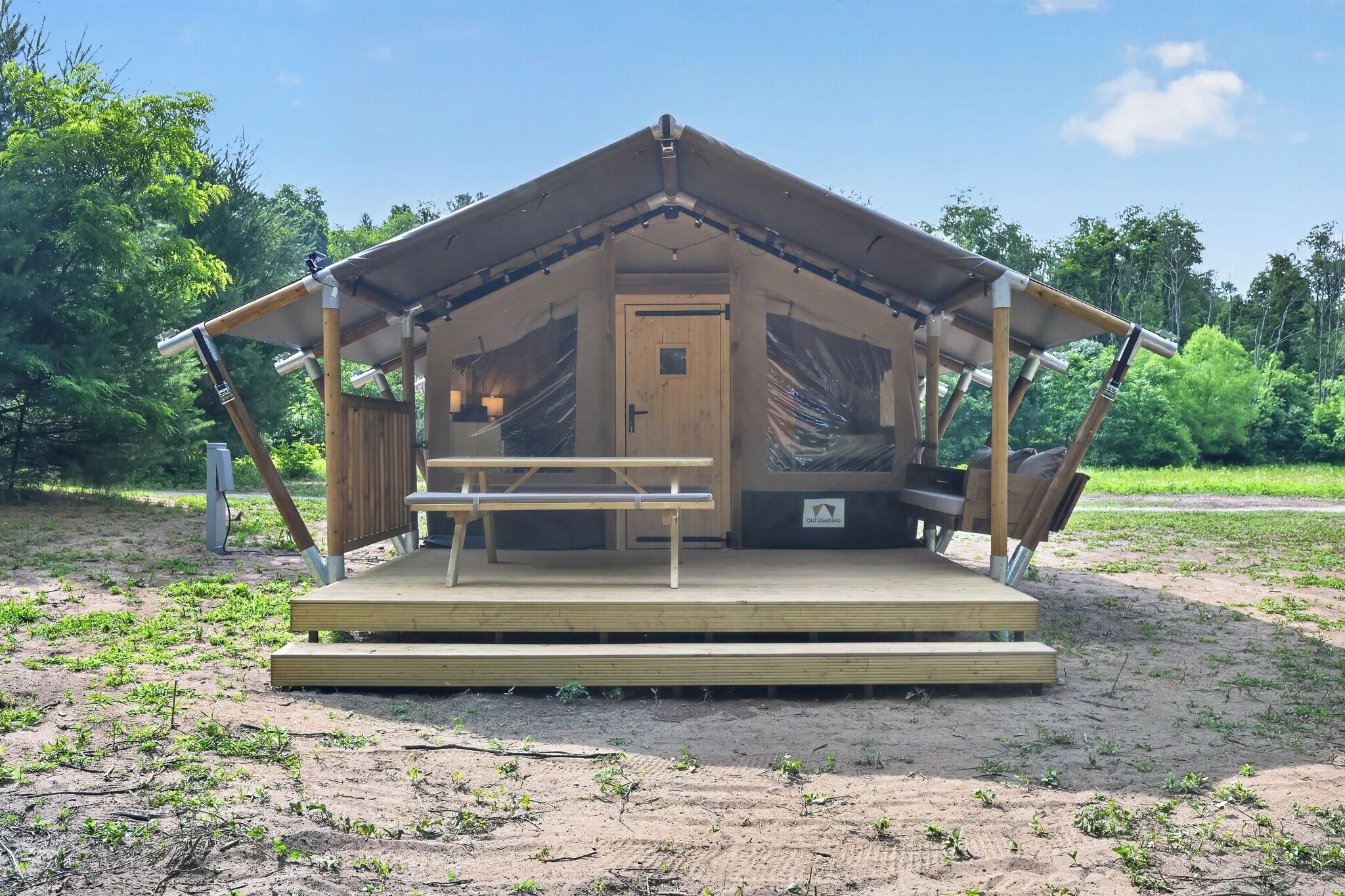 Una cabaña de madera con un banco, una puerta y una pequeña mesa.