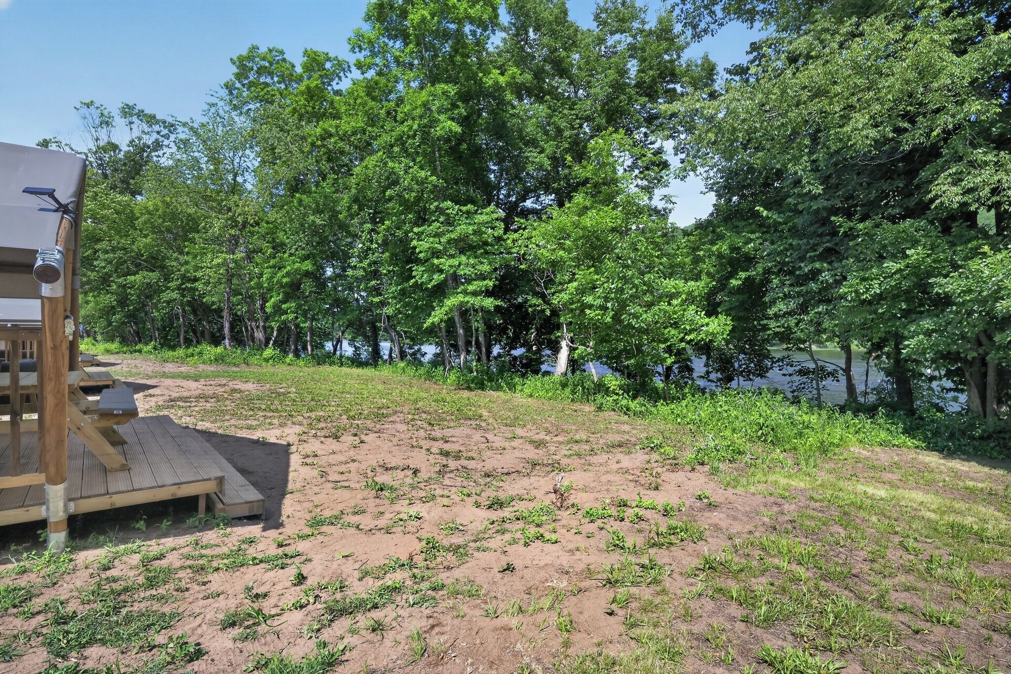 Une zone sablonne avec une terrasse en bois et une petite construction dotée d’un panneau solaire.