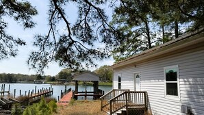 Una cabaña junto al lago con un muelle, un pequeño pabellón y una escalera de madera que lleva a la cabaña.