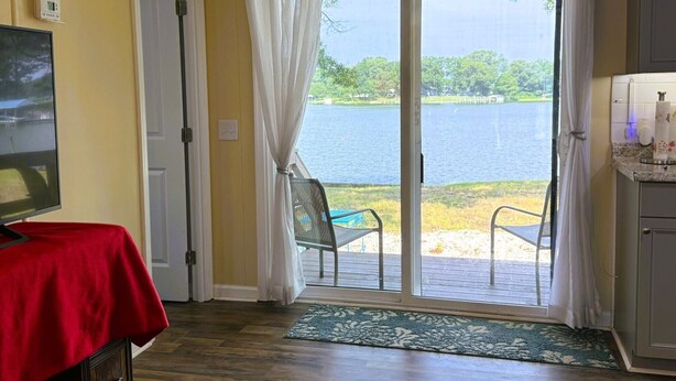 Una habitación con puerta de vidrio corrediza que da a una terraza con vista al lago.