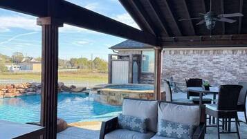 An outdoor patio with a pool, seating, and a view of the landscape.