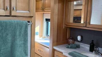 A compact kitchen with wooden cabinets, a countertop, and a window.