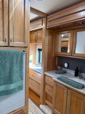 A compact kitchen with wooden cabinets, a countertop, and a window.