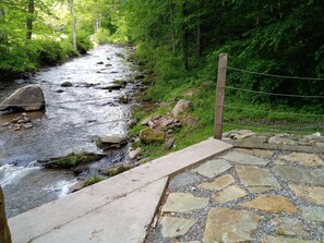Un chemin de pierres menant à une rivière, avec une clôture en bois et un poteau en bois.