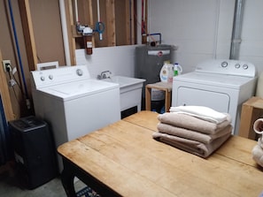 A laundry room with a washing machine, a dryer, a sink, and a wooden table with towels.