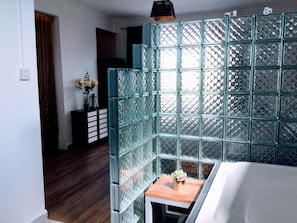 A room with a glass partition, a small wooden table with a vase, and a bed. - Serene 3-bedroom Villa With Private Pool in Roches Noires (Roches Noires)
