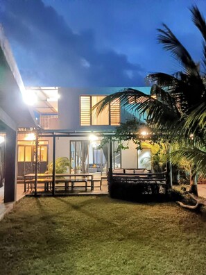 A modern building with a covered outdoor seating area, a well-maintained lawn, and a palm tree. - Serene 3-bedroom Villa With Private Pool in Roches Noires (Roches Noires)