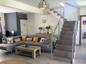 A modern living room with a grey sectional sofa, a wooden coffee table, and a staircase. - Serene 3-bedroom Villa With Private Pool in Roches Noires (Roches Noires)