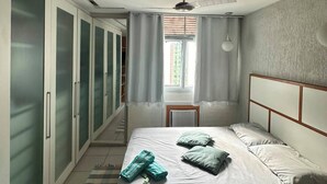 A bedroom with a bed, a window with curtains, a ceiling fan, and a wardrobe. - Carioca Corner (Rio de Janeiro)