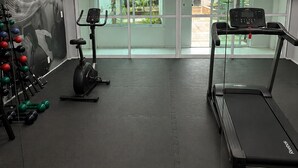A gym with treadmills, an elliptical, and a weight rack. - Carioca Corner (Rio de Janeiro)