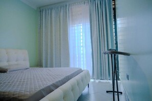 Een kamer met een bed, een radiator en een raam met gordijnen.