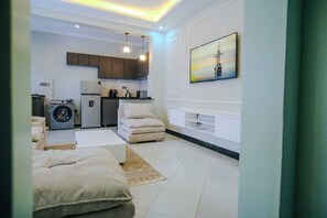 Eine moderne Wohnung mit Wohnzimmer, Küchenzeile und einem Bild an der Wand.