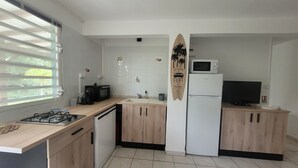 Eine moderne Küche mit Gasherd, Mikrowelle und Kühlschrank, inklusive einer Surfbret-Dekoration.
