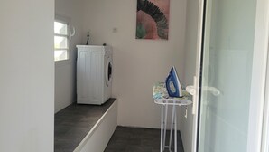 Ein Waschbereich mit Waschmaschine, Bügelecke und einem Bild an der Wand.