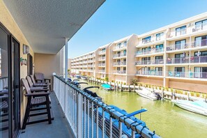 Ein Balkon mit Stühlen, Blick auf einen Yachthafen mit Booten und ein mehrstöckiges Gebäude mit Balkonen.