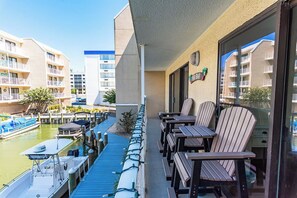 Ein Balkon mit Sitzgelegenheit im Freien, Blick auf einen Yachthafen und Spiegelungen von Gebäuden.