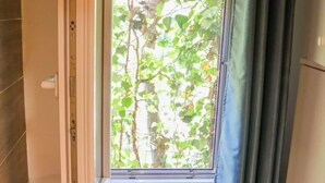 Una stanza con un'ampia finestra, un pavimento in legno e una porta con maniglia.