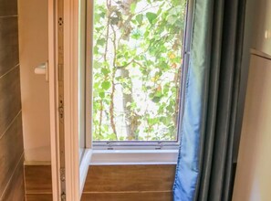 Ein Zimmer mit großem Fenster, Holzboden und einer Tür mit Griff.