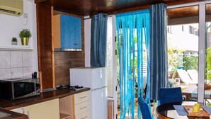 Una cucina compatta con forno a microonde, fornelli e pensili, che si apre su un'area pranzo con tavolo e sedie.