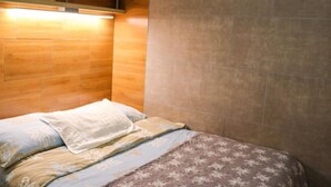 Una camera da letto con una testiera in legno, un letto con biancheria decorata e una lampada fissata al muro.