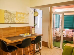 A dining area with a wooden table, black chairs, a clock, and a view of a balcony with a sofa. - two bedroom apartment Paula (Zadar)