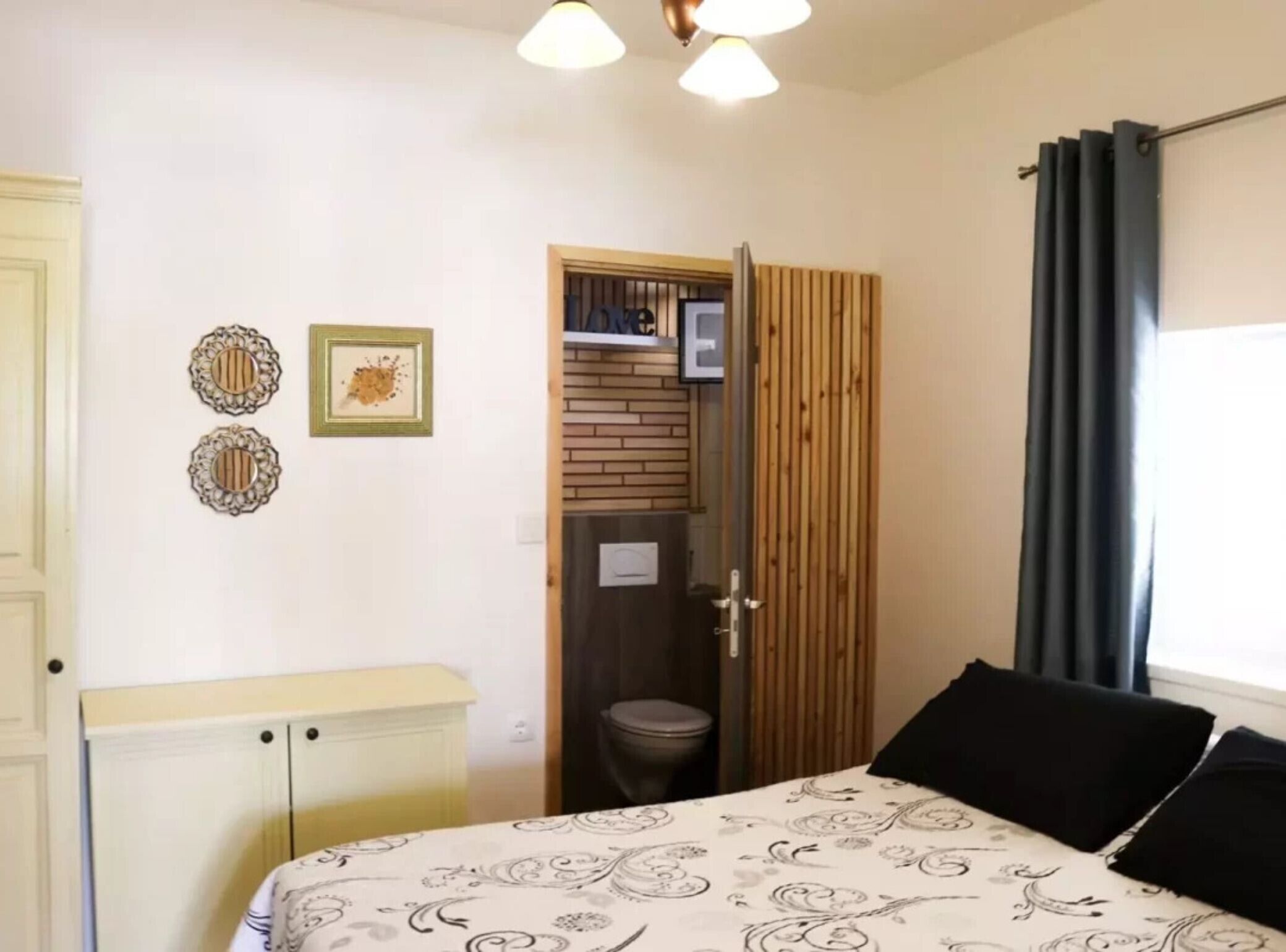 A bedroom with a bed, a wardrobe, a door, and a window with curtains.