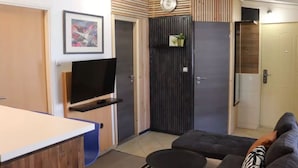 A modern living room with a flat-screen TV, a sofa, a coffee table, and a door with a vertical wooden panel design. - two bedroom apartment Mirjam (Zadar)