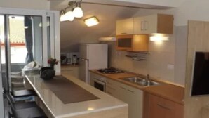 A modern kitchen with a central island, built-in appliances, and a bar area. - two bedroom apartment Ljiljana (Zadar)