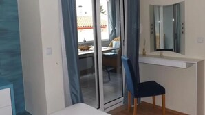 A bedroom with a sliding glass door, a desk, a chair, a mirror, and a white bedside table. - two bedroom apartment Ljiljana (Zadar)