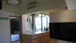 A hotel room with a bed, a TV, a wooden counter, and a window with curtains. - two bedroom apartment Ljiljana (Zadar)