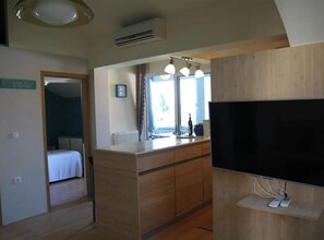 Ein Hotelzimmer mit Bett, Fernseher, Holztisch und Fenster mit Vorhängen.
