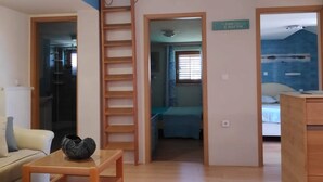 A room with a wooden table, a sofa, a ladder, and a sign on the wall. - two bedroom apartment Ljiljana (Zadar)