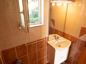 Een badkamer met een raam, een wastafel en betegelde muren.