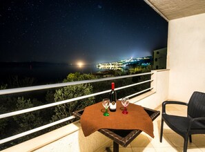 Een balkon met een tafeltje gedekt voor twee personen, een fles wijn en twee glazen.