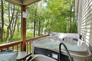 A hot tub on a wooden deck with a view of trees.