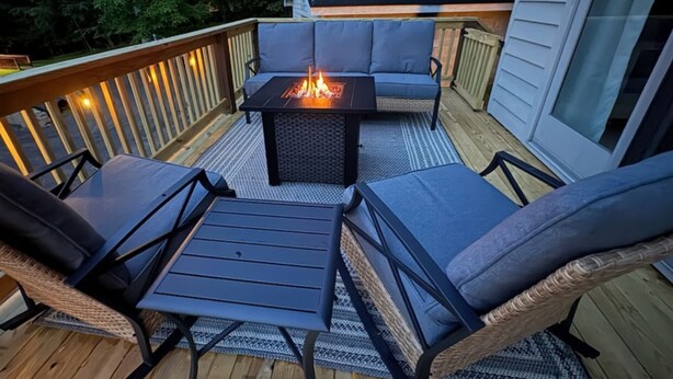 Eine Terrasse mit Feuerstelle, zwei Stühlen und einer Couch.