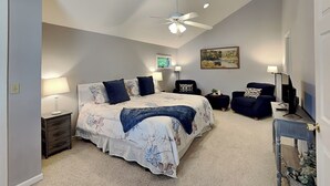 A bedroom with a bed, nightstands, a desk, a chair, a ceiling fan, and a painting on the wall. - The Fairway Retreat (Oakland)