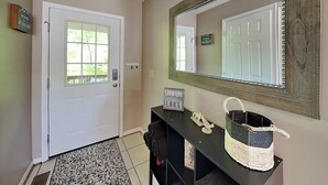 A hallway with a white door, a large mirror, a black console table with a woven basket, and a sign that reads 'LOVIN' LIFE.' - The Fairway Retreat (Oakland)