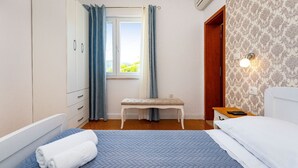 Een slaapkamer met een bed, een bankje, een kledingkast en een raam met gordijnen.