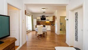 Een compact appartement met een kitchenette, een eethoek en een woonkamer.