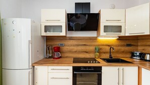 Een kleine keuken met een koelkast, magnetron, fornuis, oven en spoelbak.