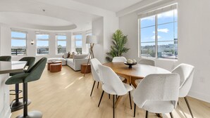 Un salon moderne avec un coin repas, de grandes fenêtres et une vue sur la ville.