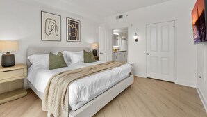 Une chambre à coucher moderne, avec un lit, des tables de chevet, un miroir et des œuvres d’art accrochées aux murs.