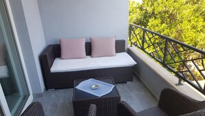 Un balcon avec un canapé, deux fauteuils en osier et une petite table sur laquelle se trouve un plateau.