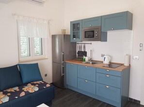 Eine kompakte Küchenzeile mit Kühlschrank, Mikrowelle, Spüle und blauen Schränken.